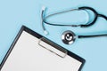 Blank clipboard with stethoscope on blue background Royalty Free Stock Photo