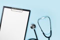 Blank clipboard with stethoscope on blue background Royalty Free Stock Photo