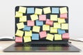 Blank colored reminder notes on laptop display on light wood office table. 3D rendering