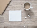 Blank compact disc , arphones,notebook and coffee on wooden background