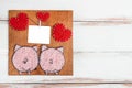 Blank for congratulations in the form of a panel with hearts and pink pigs on a wooden white background