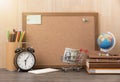 Blank cork board with alarm clock, book, money on wooden.