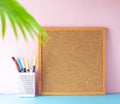 Blank cork board frame, mood board, on pink wall and blue table, bright summer and colorful workspace for girl, student or artist Royalty Free Stock Photo