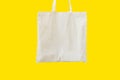 Blank cotton white shopper tote bag on yellow background. Mock up template