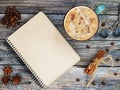 Blank craft sketchbook with cup of coffee, spoon and anise, cinnamon, beabs of coffe on vintage wooden table. Flat lay Royalty Free Stock Photo