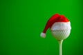 A blank for the design of a postcard for a golfer for the new year or Christmas. Golf ball on a tee with a red santa claus hat. Royalty Free Stock Photo