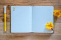 Blank diary notebook, yellow flower and pen on wooden table