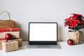 Blank display screen laptop computer with Poinsettias Christmas Flower and gift boxes on white table. Home office desk Royalty Free Stock Photo