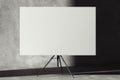 Blank easel with white canvas on concrete gray background. 3D rendering.