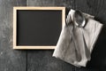 Blank, empty, black chalkboard with spoon and fork silverware and gray dish towel flat lay from above on black wooden table Royalty Free Stock Photo