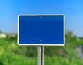 A blank empty blue sign with a green field and blue sky background
