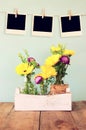 Blank empty instant photos hang on a rope over summer bouquet of flowers on the wooden table with mint background. vintage Royalty Free Stock Photo