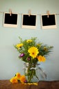 Blank empty instant photos hang on a rope over summer bouquet of flowers on the wooden table with mint background. vintage Royalty Free Stock Photo