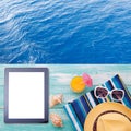 Blank empty tablet computer on beach. Trendy summer accessories on wooden background pool. Sunglasses, orange juice and Royalty Free Stock Photo