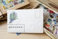 A blank envelope lying in front of a collection of postage stamps of different countries in the old box and stamp holder