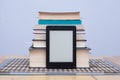 Blank eReader in front of a tower of books with bookmarks