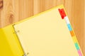 Blank file tabs in a yellow binder on wood desk mockup