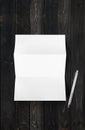 Blank folded White A4 paper sheet mockup and pen on black wood background Royalty Free Stock Photo