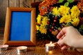 Blank frame, burning candles and flowers on table against wooden background, Space for design Royalty Free Stock Photo