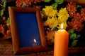 Blank frame, burning candles and flowers on table against wooden background, Space for design Royalty Free Stock Photo