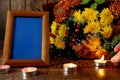 Blank frame, burning candles and flowers on table against wooden background, Space for design Royalty Free Stock Photo
