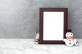 Blank frame with christmas balls and snowman decorations on marble table. Mock up for your photo or text