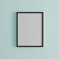 Blank frame on light blue wall mock up, vertical black poster frame on wall, picture frame isolated on a wall, mock up for
