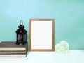 Blank frame mockup for presentation with cozy home details  on table over mint colored wall Royalty Free Stock Photo