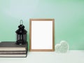 Blank frame mockup on table over green colored wall. Royalty Free Stock Photo