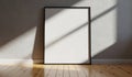 Blank framed poster leaning against a textured wall with dramatic sunlight and shadow patterns Royalty Free Stock Photo