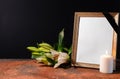 Blank funeral frame, candle and flowers on table against black background Royalty Free Stock Photo