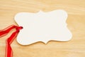 Blank gift tag with red ribbon on wood desk Royalty Free Stock Photo