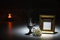 blank gilded picture frame with thurible and candle flame and white rose