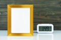 Blank golden frame and digital alarm clock on table Royalty Free Stock Photo