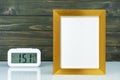 Blank golden frame and digital alarm clock on table Royalty Free Stock Photo