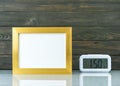 Blank golden frame and digital alarm clock on table Royalty Free Stock Photo