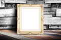 Blank golden vintage photo frame leaning at plank wood wall and