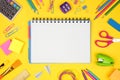 Blank graphing paper notebook with school supplies frame against yellow. Back to school. Copy space.