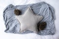 Blank gray star cushion surrounded by pine cones and a gray scarf