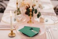 Blank green envelopes with stamps lie on a transparent plate on a set table. A lighted candle is burning on the left