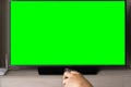 Green screen TV with defocused hand holding remote control Royalty Free Stock Photo