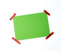 Blank green sheet of paper stuck with red sticky tape Royalty Free Stock Photo