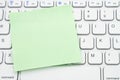 Blank green sticky note on a profile gray computer keyboard Royalty Free Stock Photo