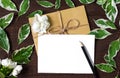 Blank greeting card and envelope with jasmine flowers, pencil and green leafs