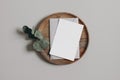 Blank greeting card, invitation and envelope mockup. Wooden plate, tray. Beige table background with dry eucalyptus