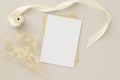 Blank greeting card invitation Mockup 5x7 on Brown envelope with dried flowers on beige background, flat lay, mockup Royalty Free Stock Photo