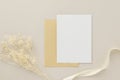 Blank greeting card invitation Mockup 5x7 on Brown envelope with dried flowers on beige background, flat lay, mockup Royalty Free Stock Photo