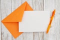 Blank greeting card with orange envelope and pen on wood Royalty Free Stock Photo