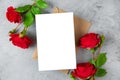 Blank greeting card with red rose flowers on gray background. Wedding invitation. Mock up. Flat lay Royalty Free Stock Photo