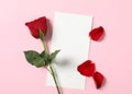 Blank greeting card, rose and petals on pink background, flat lay. Valentine`s day celebration Royalty Free Stock Photo